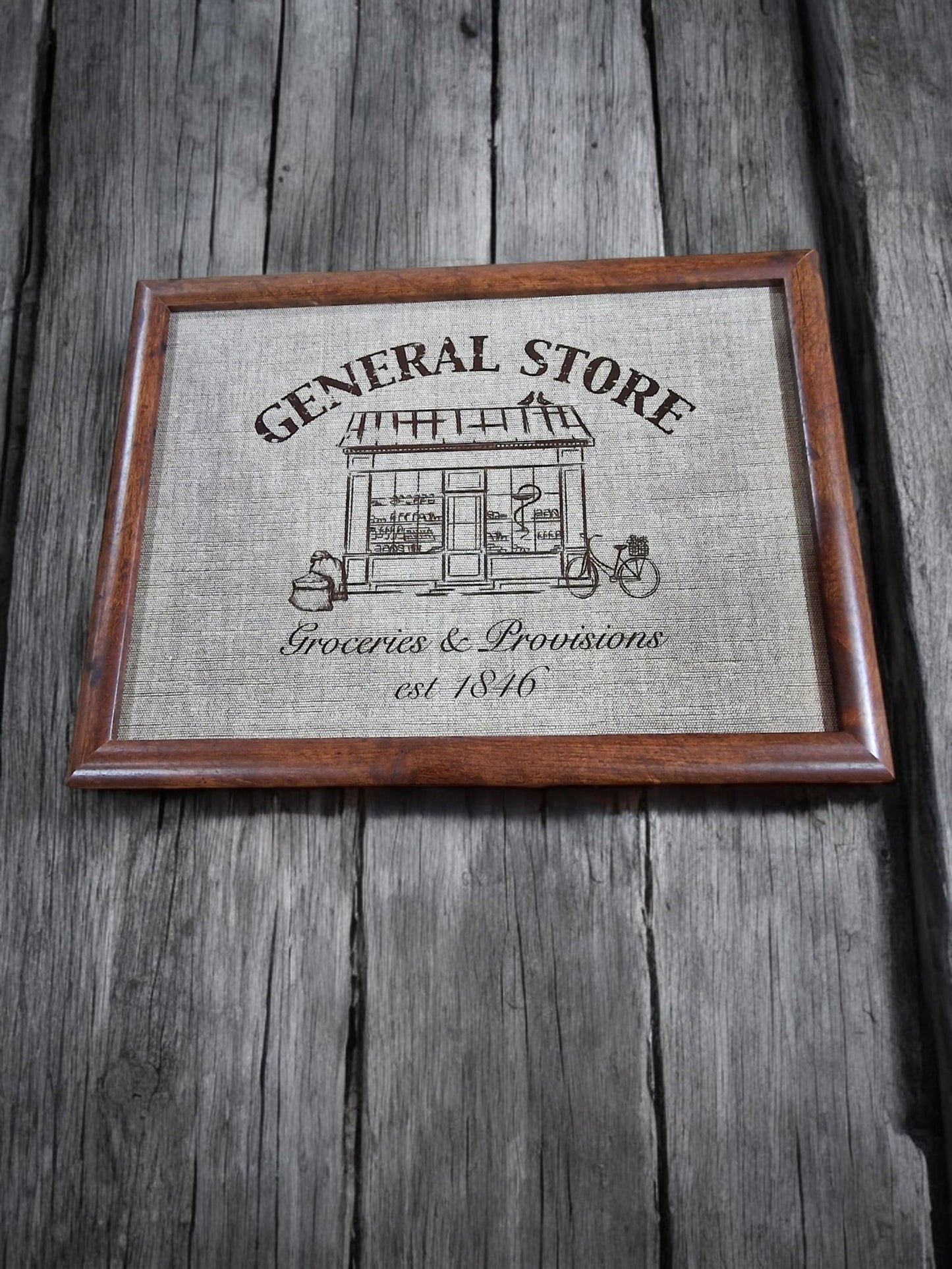 Framed print lap tray of a vintage general store design, featuring a building illustration, "Groceries & Provisions," and "est. 1846".