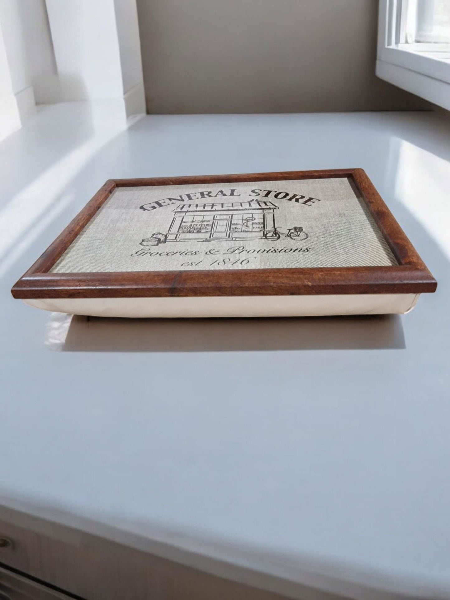 Framed print lap tray of a vintage general store design, featuring a building illustration, "Groceries & Provisions," and "est. 1846".