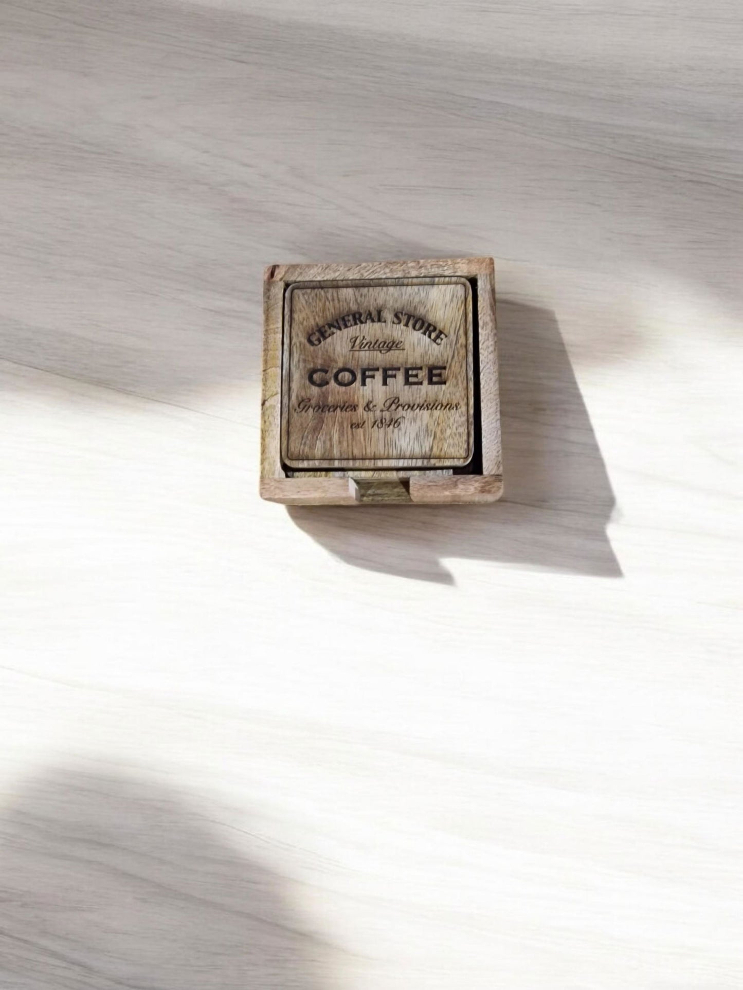 Wooden coaster holder with "General Store Coffee" logo and scattered coffee beans.