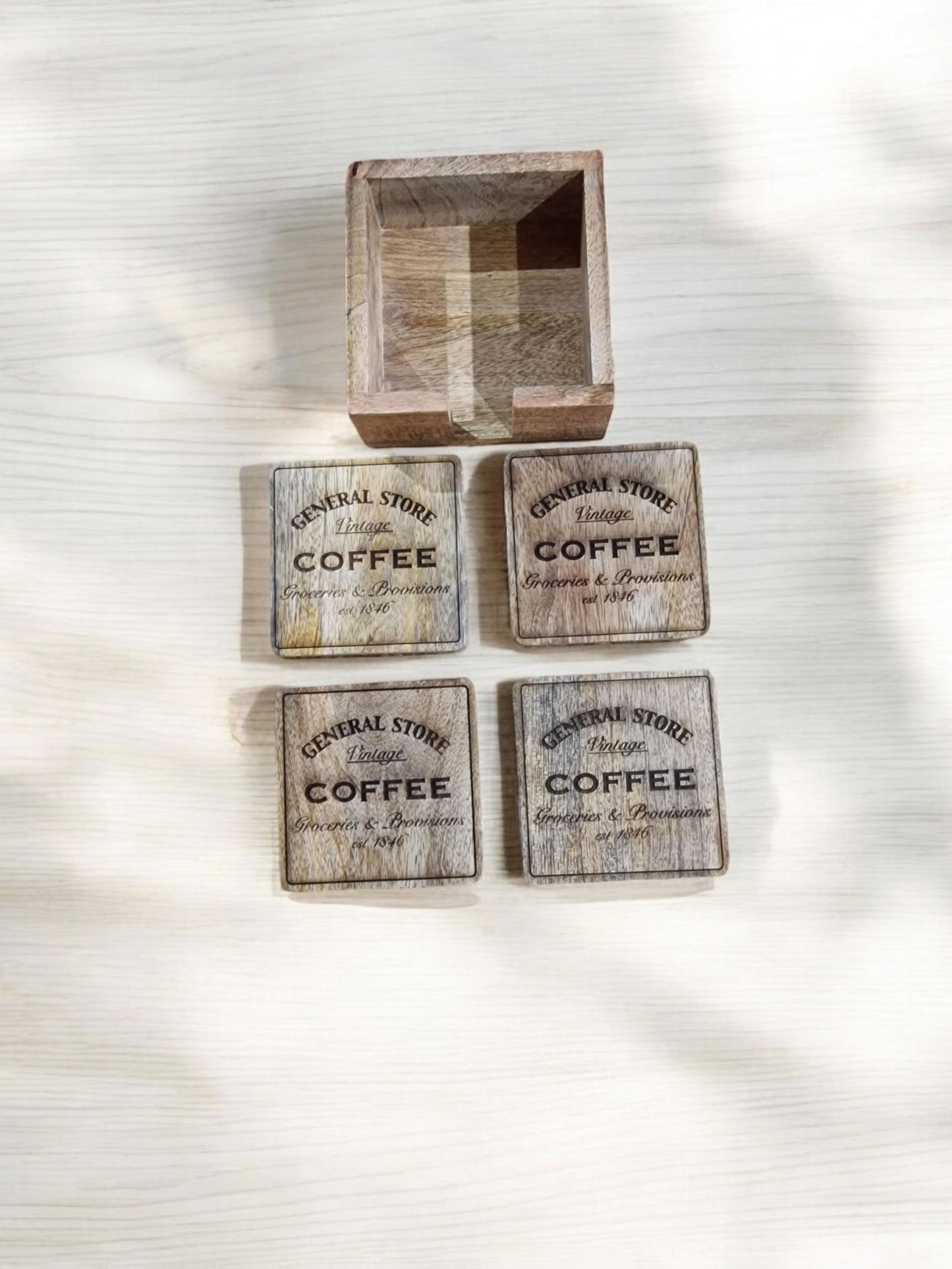 Wooden coaster holder with "General Store Coffee" logo and scattered coffee beans.