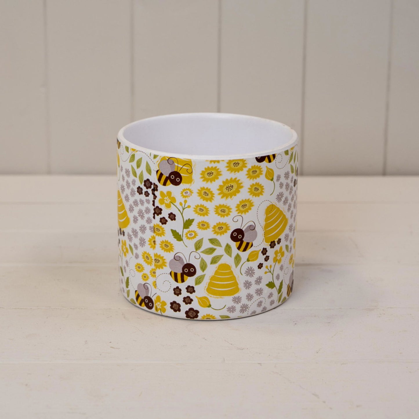 Round white planter with a yellow and gray bee and flower pattern.