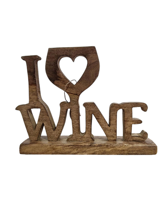 Wooden decorative sign that says "I love wine" with a heart-shaped cut-out in a wine glass design, situated on a woven placemat.