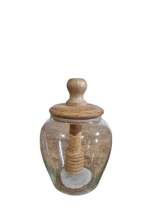 Clear glass jar with a wooden lid and dipper, sitting on a burlap table.