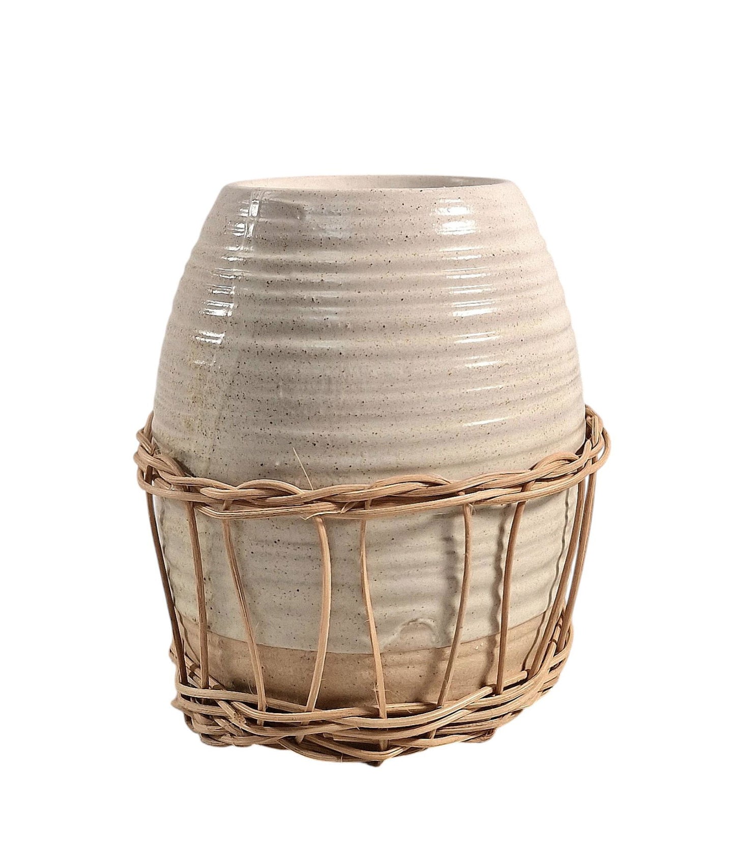 Ceramic oil burner with natural rattan detail, featuring a lit tealight inside, styled on a wooden surface with a floral arrangement in the background