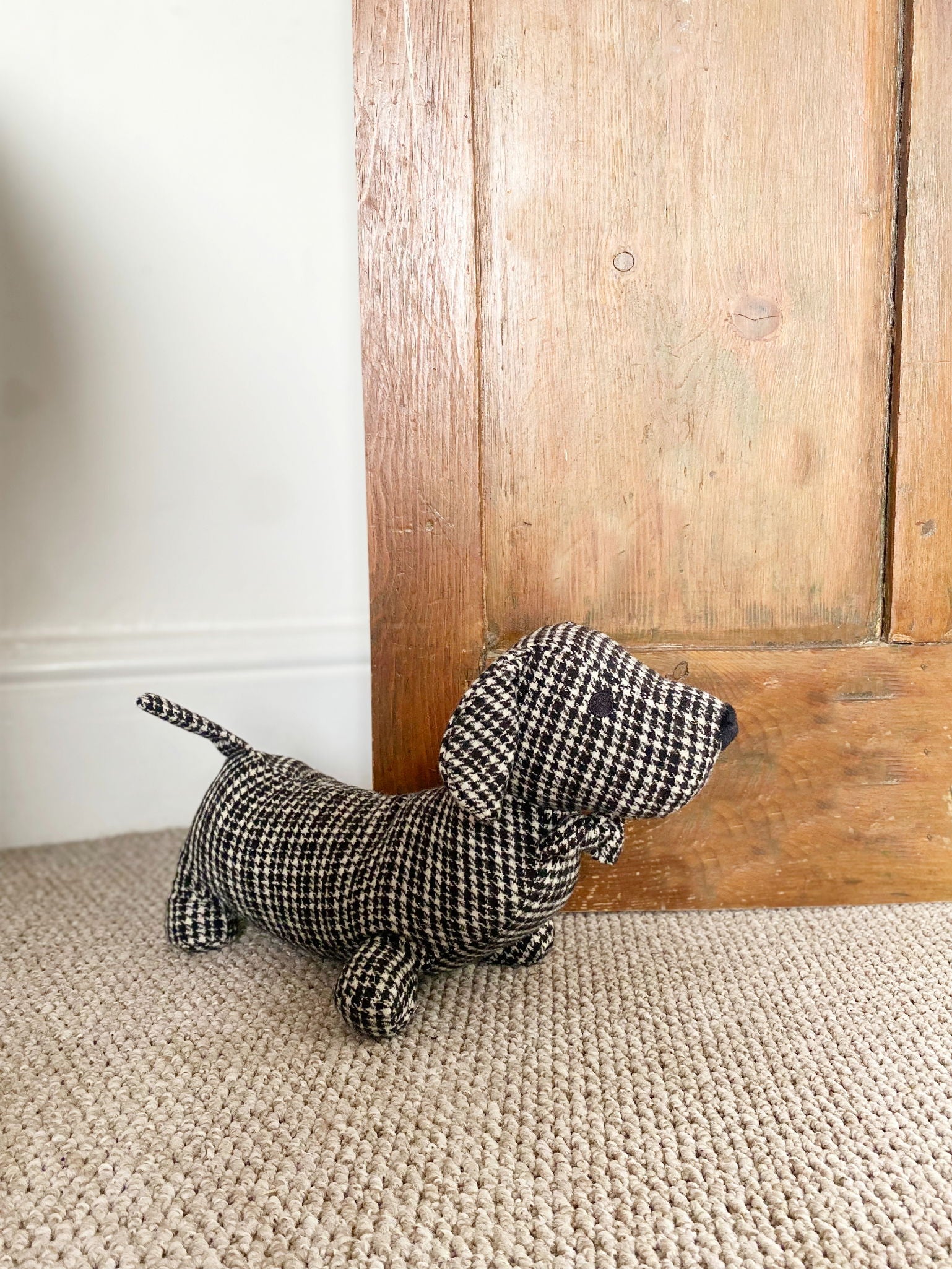 Fabric sausage dog doorstop in a grey and black herringbone pattern