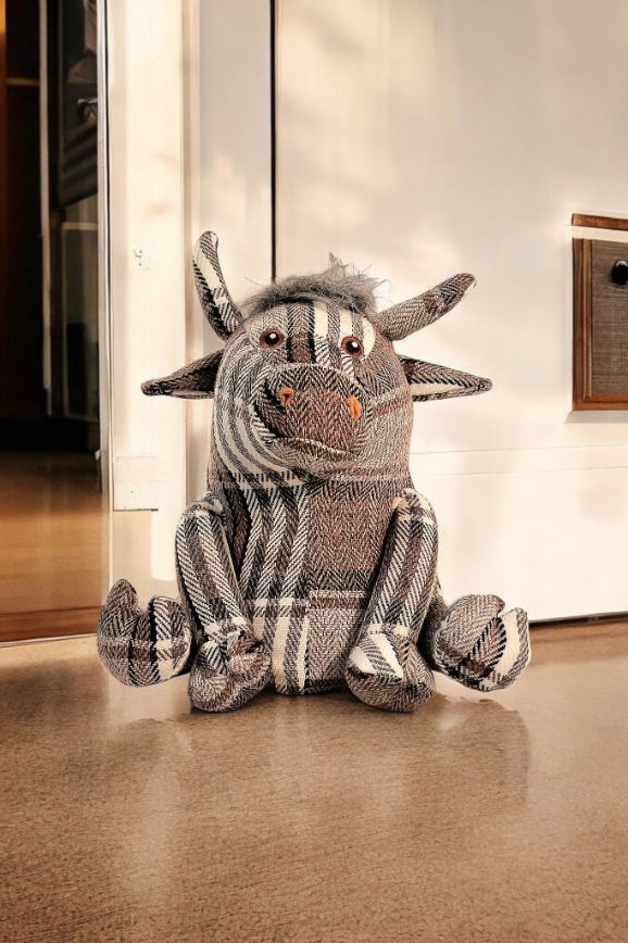 Grey tartan fabric bull doorstop with soft horns and button eyes, used as a charming and functional home decor accessory