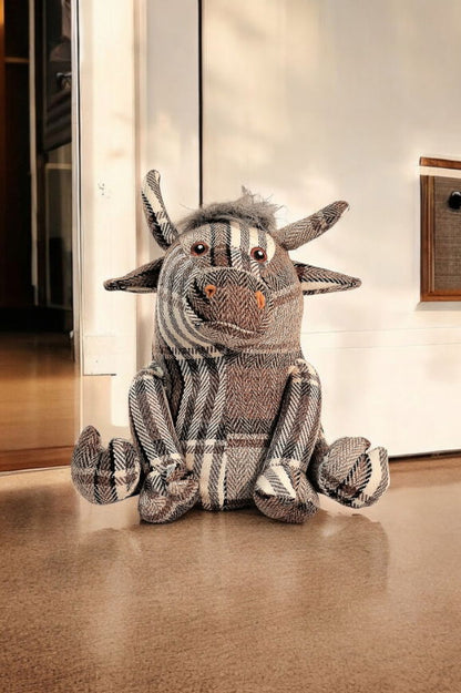 Grey tartan fabric bull doorstop with soft horns and button eyes, used as a charming and functional home decor accessory